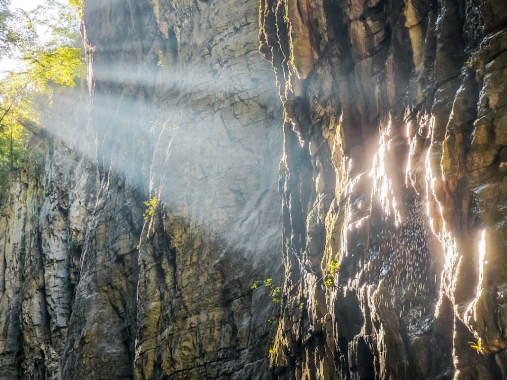 Sunbeams pierce through a rocky canyon wall