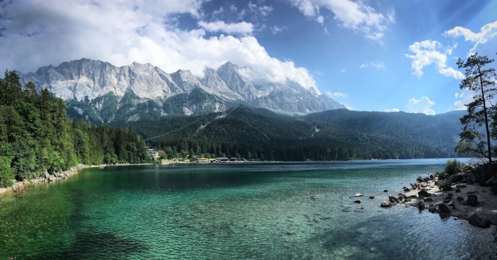 A lake surrounded by trees and mountains under a cloudy sky