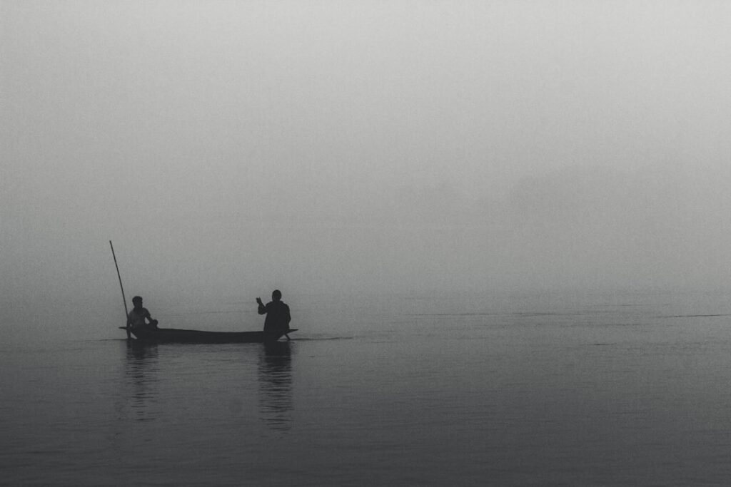 Silhouetted of two persons riding on boat