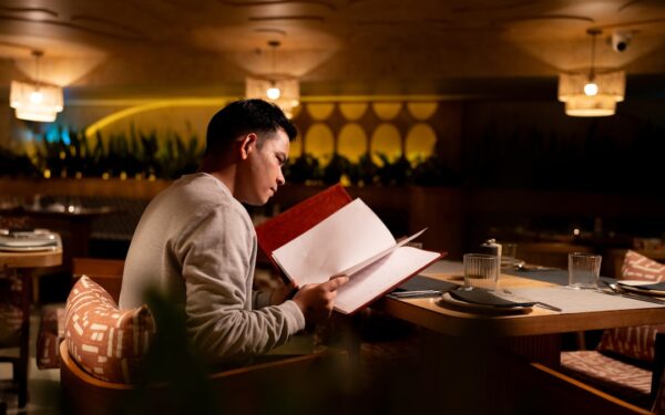Man reading a menu at a restaurant table. — Boomtown Kitchen