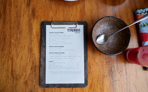 Menu on a wooden table with food items. — Stonecat Café