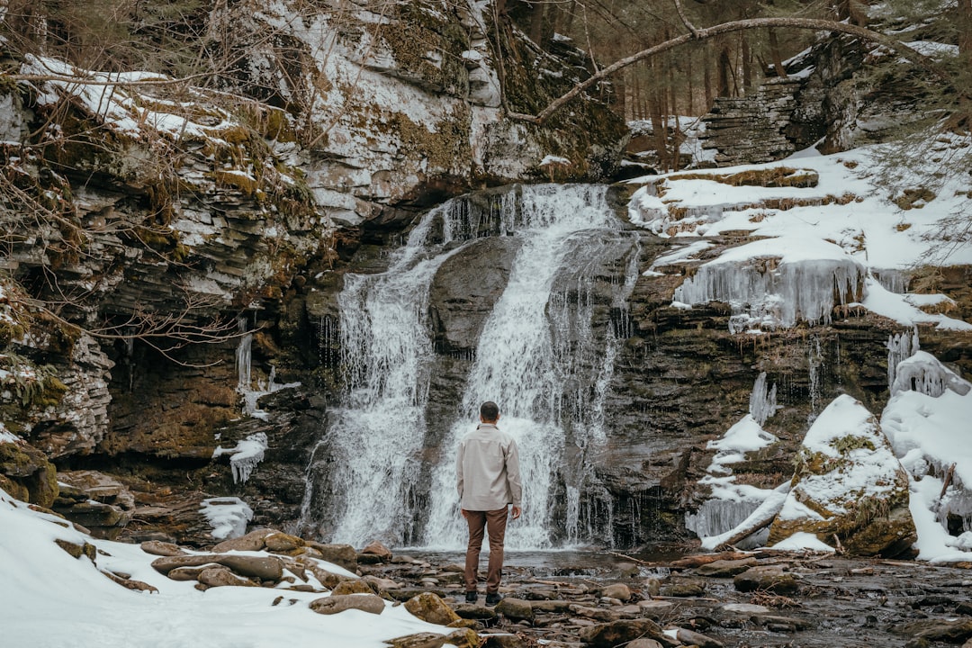 A person standing in front of a waterfall — Cayuga Lake Wine Trail: The Complete Tasting Guide