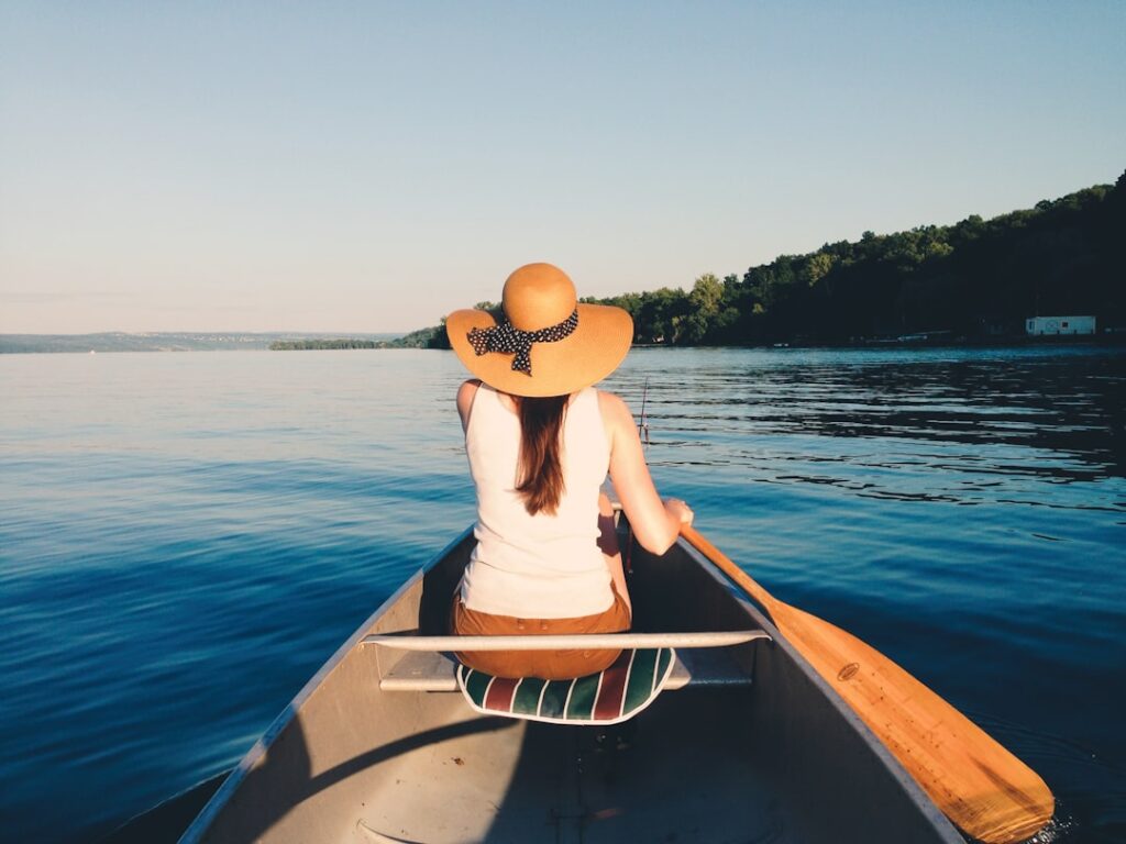 Woman wearing sunhat riding boat on body of water