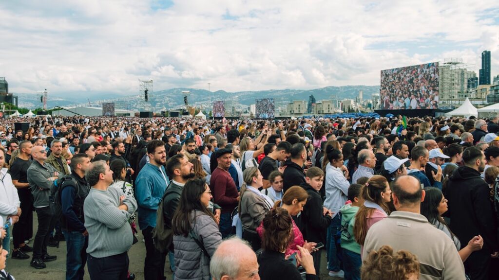 Large crowd gathered outdoors watching a distant screen
