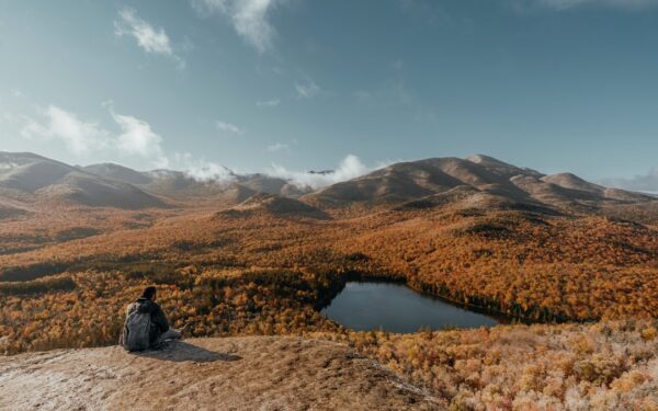 A person sitting on a rock looking at a lake surrounded by mountains — The Keuka Lake Outlet Trail: A Peaceful Gorge Walk