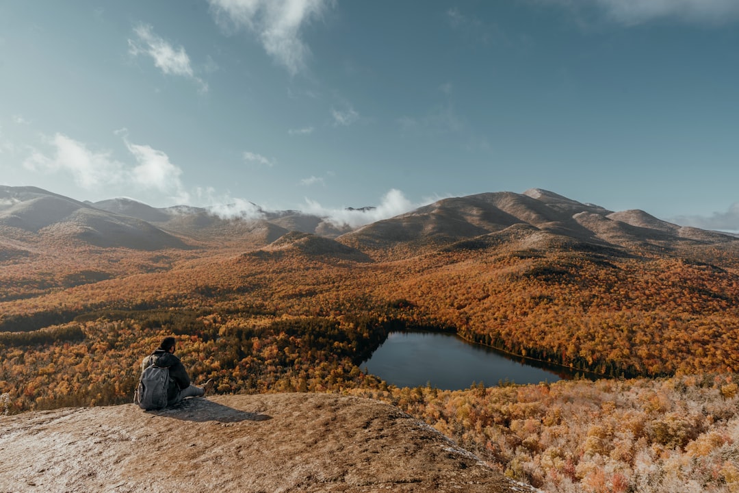 A person sitting on a rock looking at a lake surrounded by mountains — The Keuka Lake Outlet Trail: A Peaceful Gorge Walk