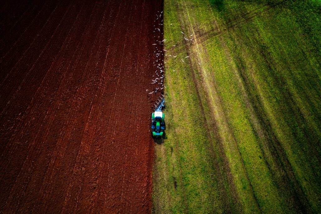 A tractor is driving through a green field